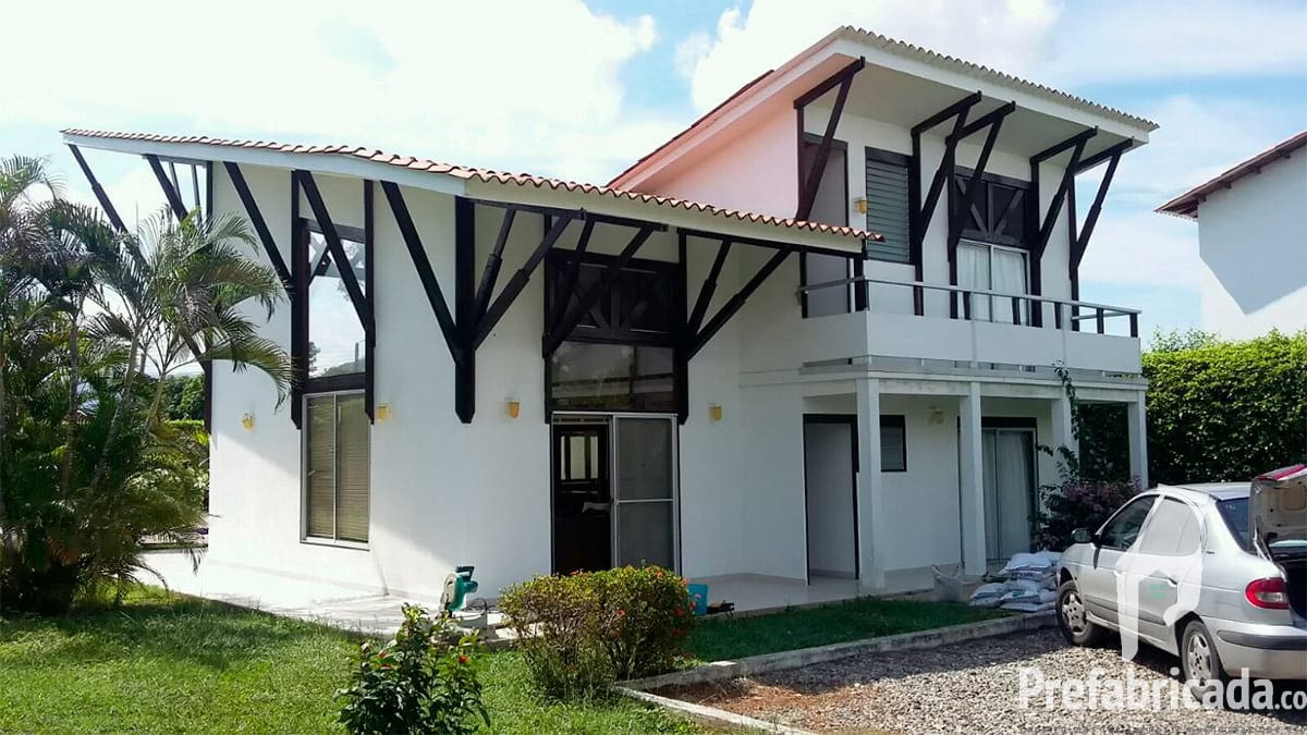 Casa prefabricada moderna de dos plantas con estructura de madera visible, cochera y fachada blanca
